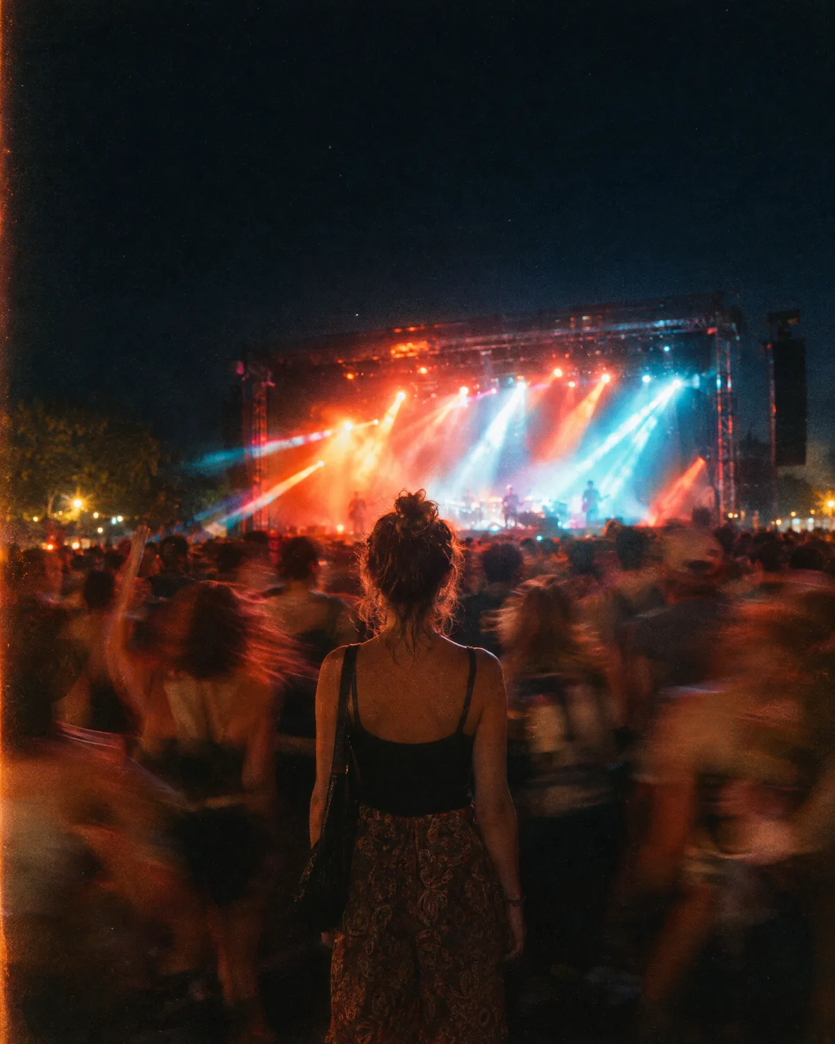 A crowd facing a lit stage at a night show
