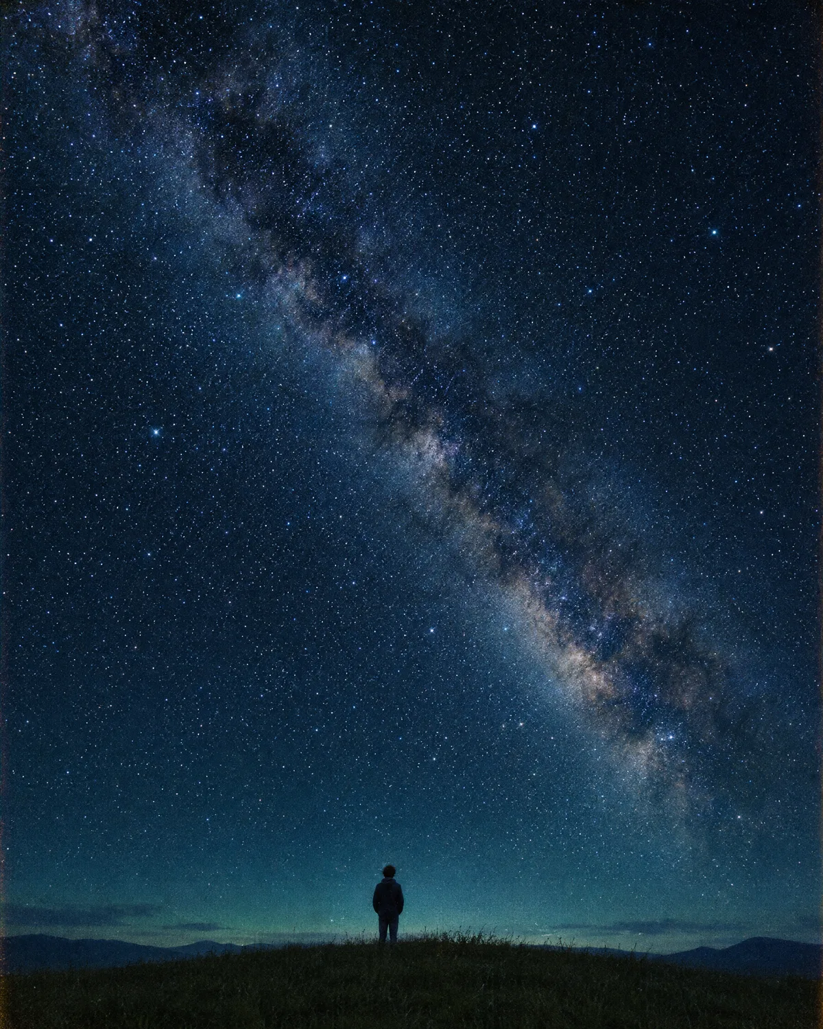A lone figure on a hill under the Milky Way